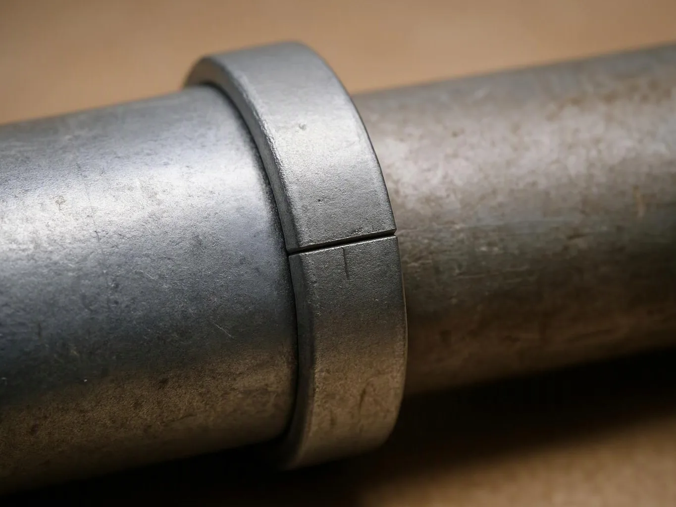 A metal clamp ring wraps around a gray pipe in a close-up view
